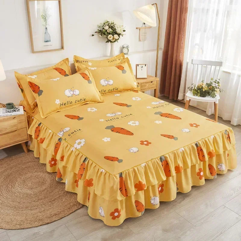 Une jupe de lit jaune à motif carotte orange et ourlet froncé, exposée sur un lit.