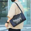 A person is holding a dark blue and gray sports duffel bag with white stripes against a glass background.
