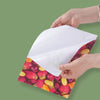 Hands are holding a sheet of glossy self-adhesive inkjet photo paper with a vibrant pattern of strawberries and citrus fruits