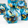 A close-up of a set of blue and black liquid core resin dice with gold numbering and dragon eye designs.