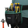 A black tool waist bag with a green trim and belt, holding various hand tools like pliers and knives.