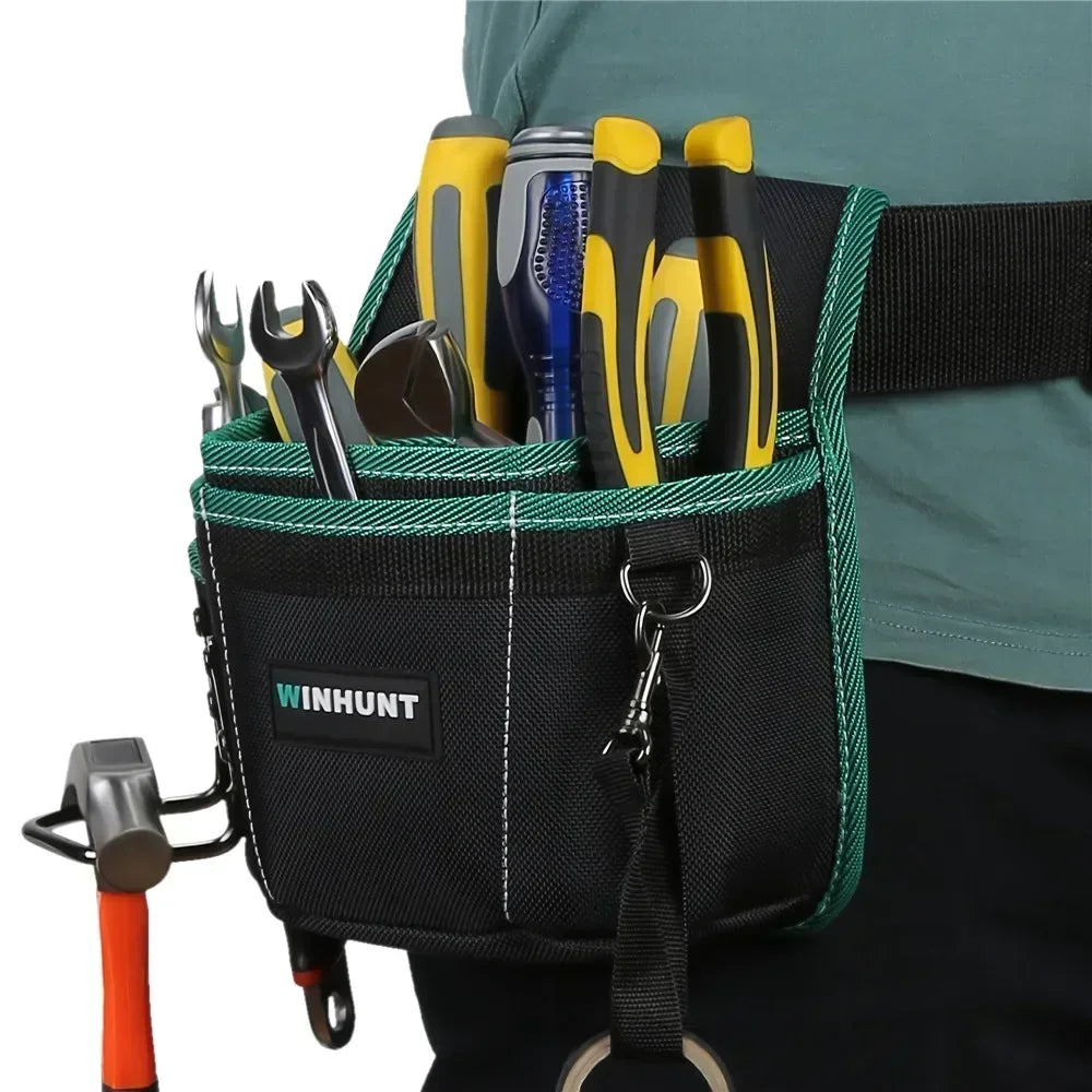 A black tool waist bag with a green trim and belt, holding various hand tools like pliers and knives.