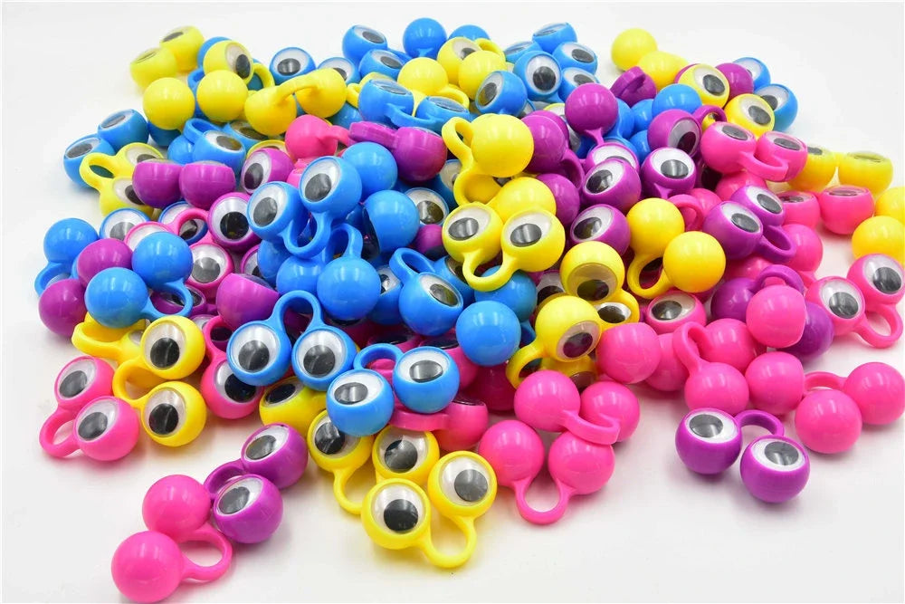 A large pile of 100 colorful eye finger puppet rings in various shades of blue, yellow, and pink for party favors.
