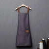 A dark gray waterproof kitchen apron hanging on a wooden hanger.
