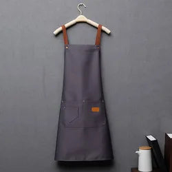 A dark gray waterproof kitchen apron hanging on a wooden hanger.