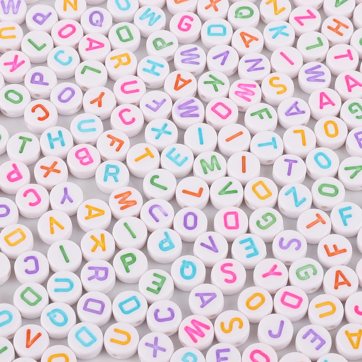 A collection of white and colored acrylic alphabet letter beads for jewelry making