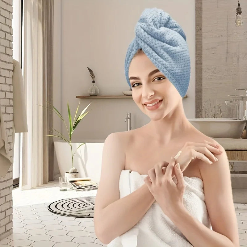 Une femme portant un foulard de serviette en microfibre bleu clair, souriante et tenant une serviette blanche.