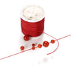 Red nylon macramé cord in a spool with several finished strands for jewelry making