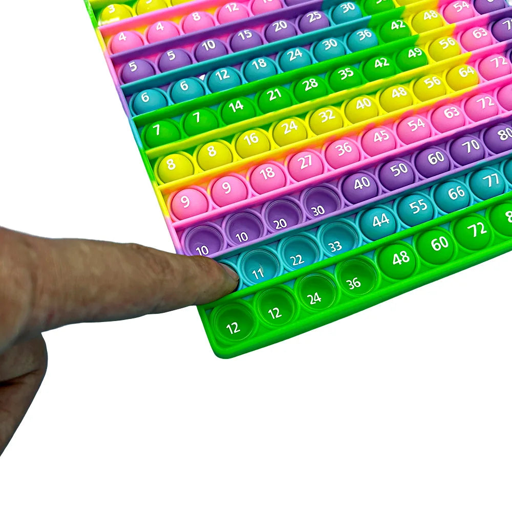 A hand is holding a colorful push bubble math game with numbered bubbles for addition and multiplication learning.