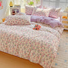 A floral duvet cover set featuring pink and purple floral patterns on a bed with matching pillows.