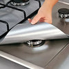 A hand is placing a silver square liner protector onto a gas hob surface.