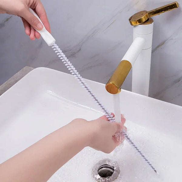 Une main utilise un déboucheur et un outil pour déboucher un évier.