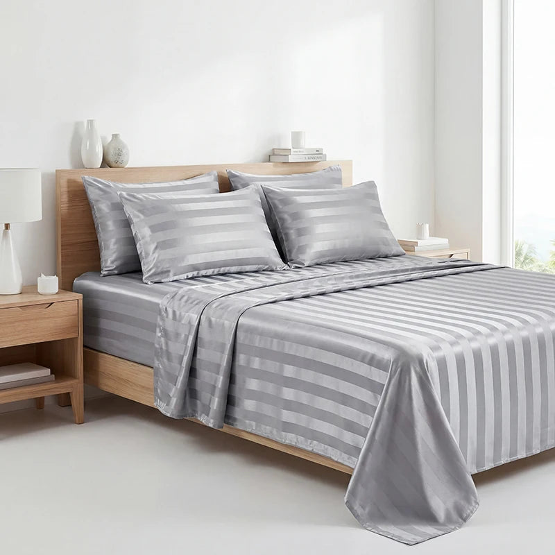 A set of four striped satin bed sheets in gray are displayed on a wooden bed with pillows and bedding.