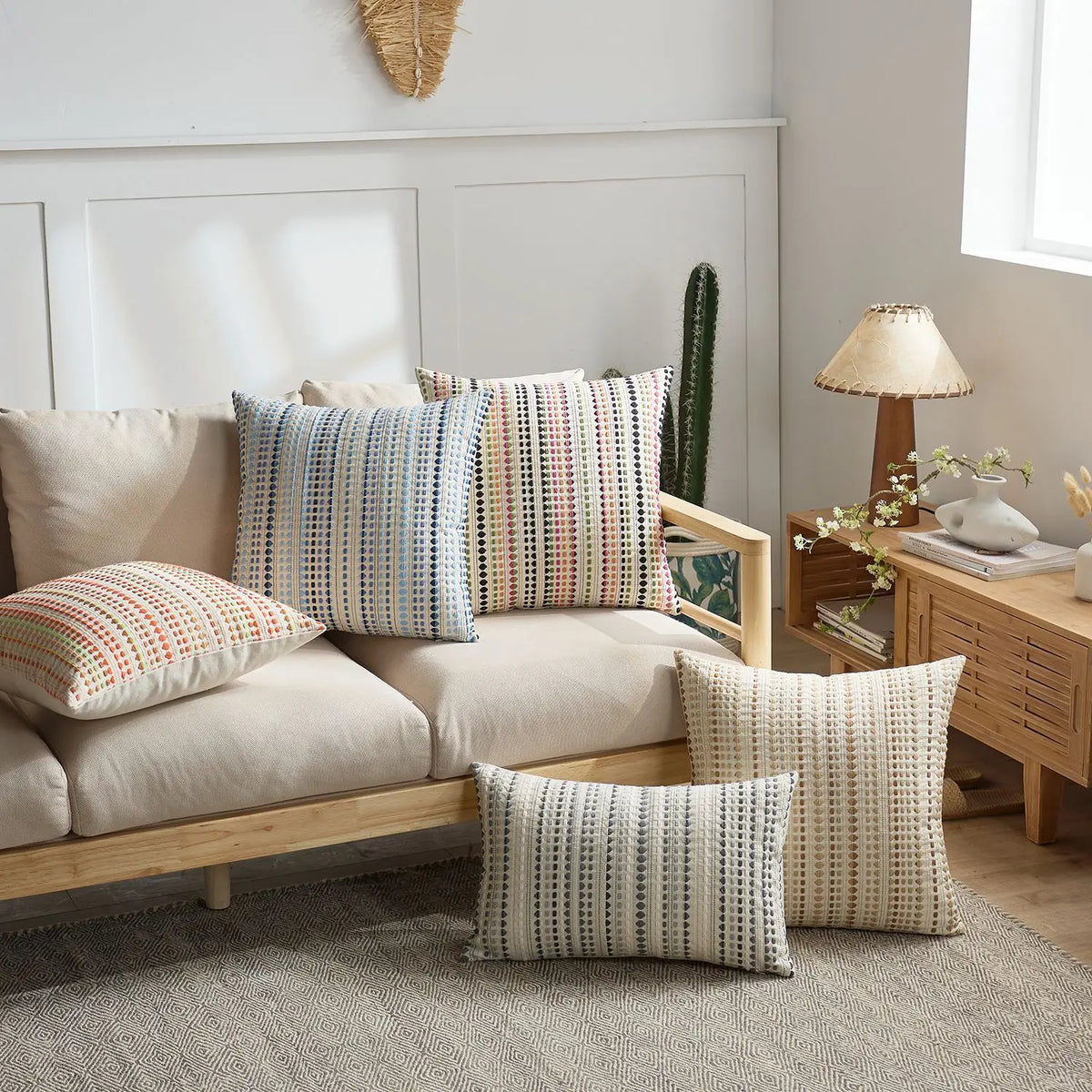 A set of two bohemian linen pillow covers in striped patterns resting on a light-colored sofa.