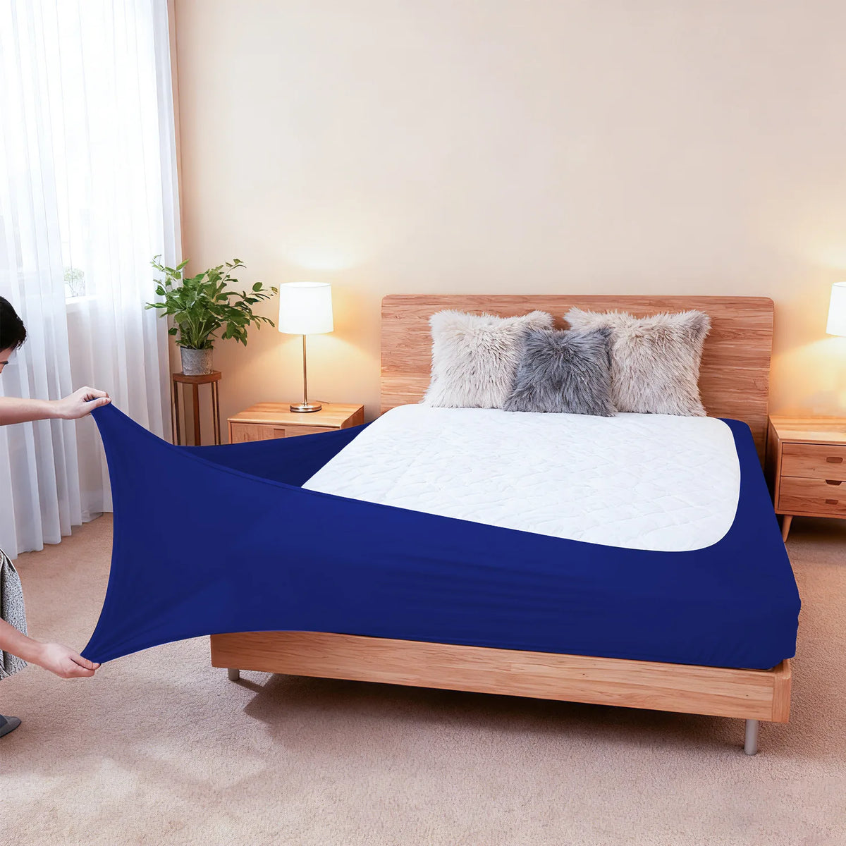 A deep blue stretch-fit box spring cover with an elastic edge is displayed on a wooden bed frame.