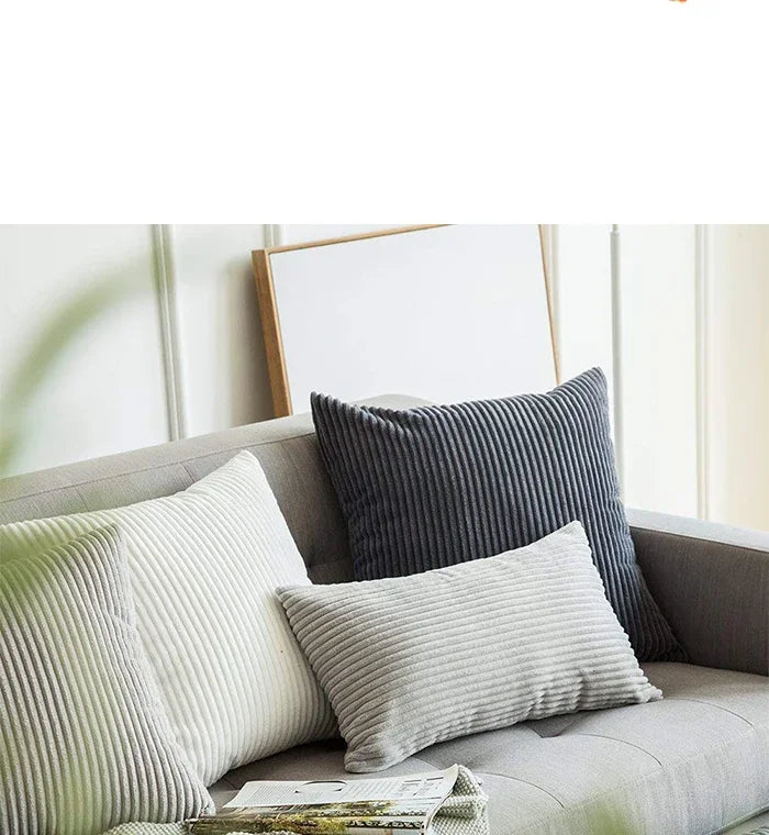 A set of striped velvet corduroy cushion covers on a gray sofa with a framed picture.