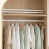 A display of white and light green clothing hanging on a wooden rack inside a shower niche.