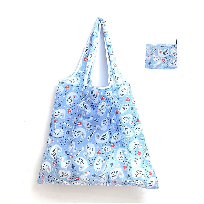 A light blue reusable shopping tote bag featuring a pattern of white and red hearts and birds.