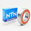 A blue box of NTN bearings next to a silver deep groove ball bearing.