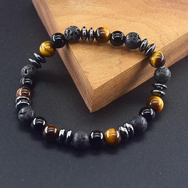 Una pulsera hecha de piedras de ojo de tigre negro y dorado brillante sobre una superficie de madera.