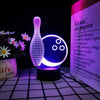 A glowing glass-shaped night light illuminates a piece of paper, demonstrating a 3D illusion effect.