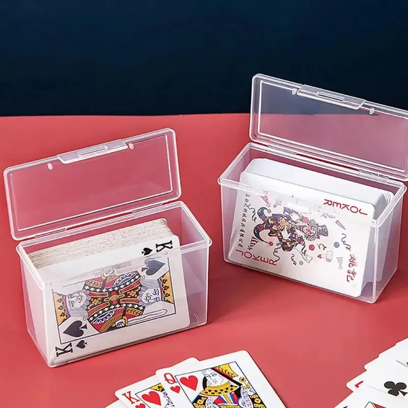 Clear plastic storage box containing playing cards and business cards on a red surface.