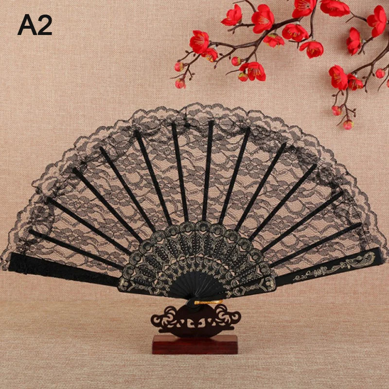 A black lace folding fan with a floral design displayed on a wooden stand against a beige background.