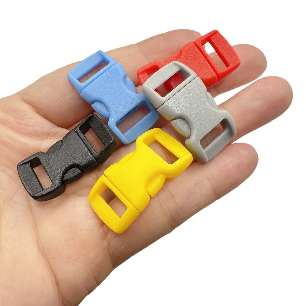 A hand holds several plastic side-release buckles in various colors including red, blue, gray, and yellow.