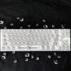 A translucent PC keycap for a mechanical keyboard is displayed on a black surface with scattered crystal shards.
