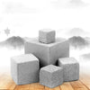 Three gray natural mineral molar stones stacked on a wooden surface against a misty mountain background.