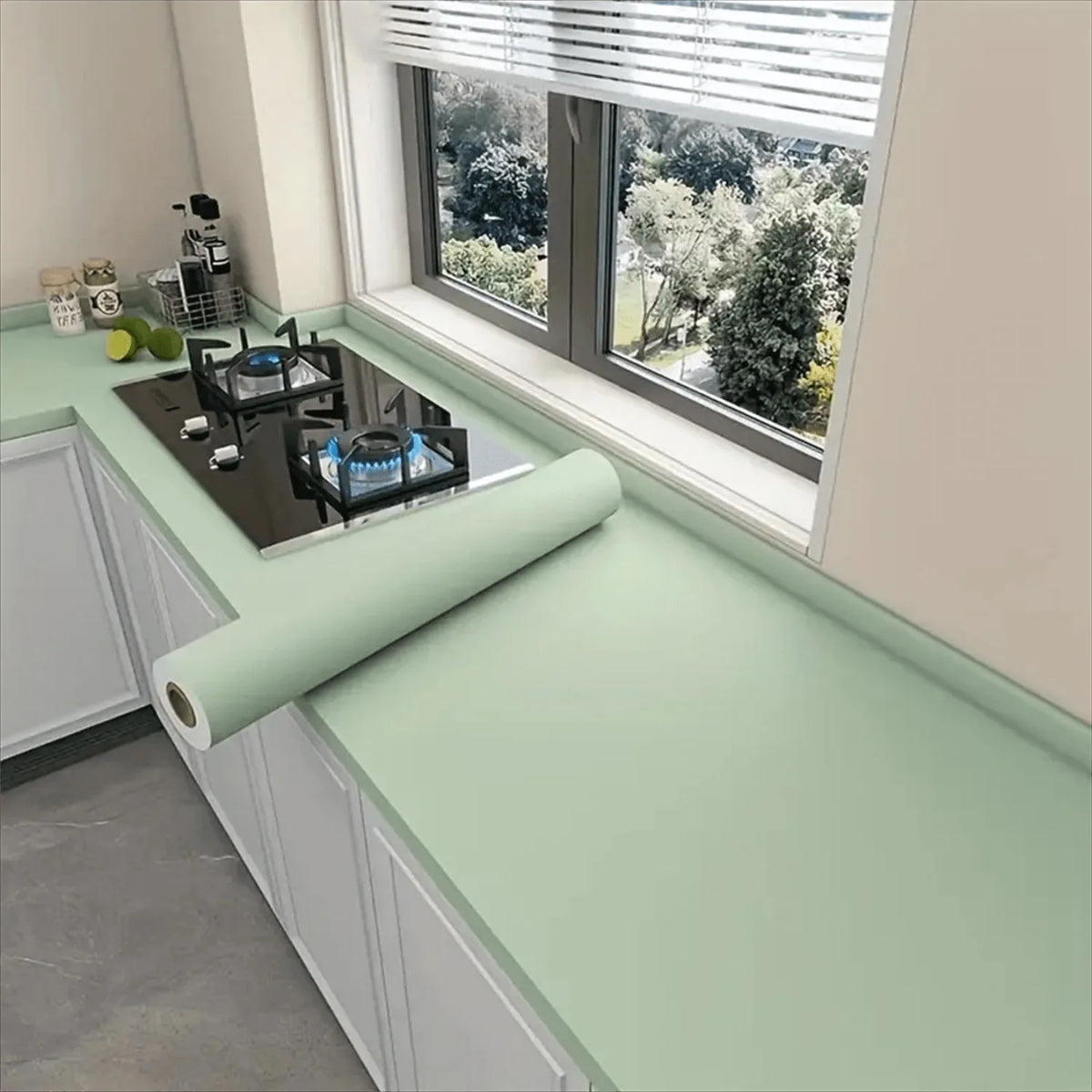 A kitchen window view showing a matte green vinyl film applied to the windowsill and surrounding cabinetry.