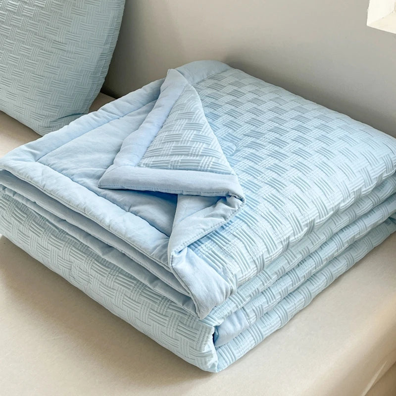 Light blue breathable waffle-weave summer quilt folded on a white surface.
