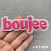 Pink embroidered patch spelling the word boujee held in a hand