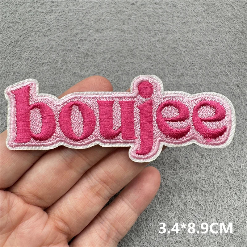 Pink embroidered patch spelling the word boujee held in a hand