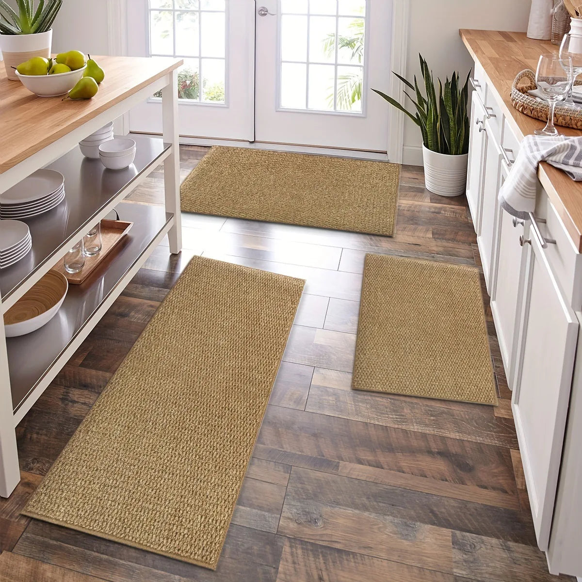 A rectangular natural fiber kitchen runner rug in beige sits on a dark wood floor next to white cabinetry.