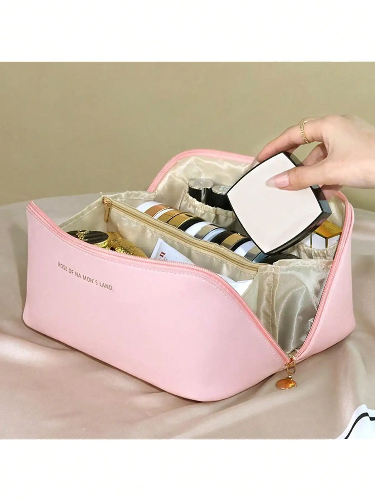 A pink leather travel makeup organizer bag is shown open, displaying various cosmetic items and a compact mirror.