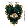 A dark green heart-shaped patch embroidered with black fur and a sparkling gold eye design.