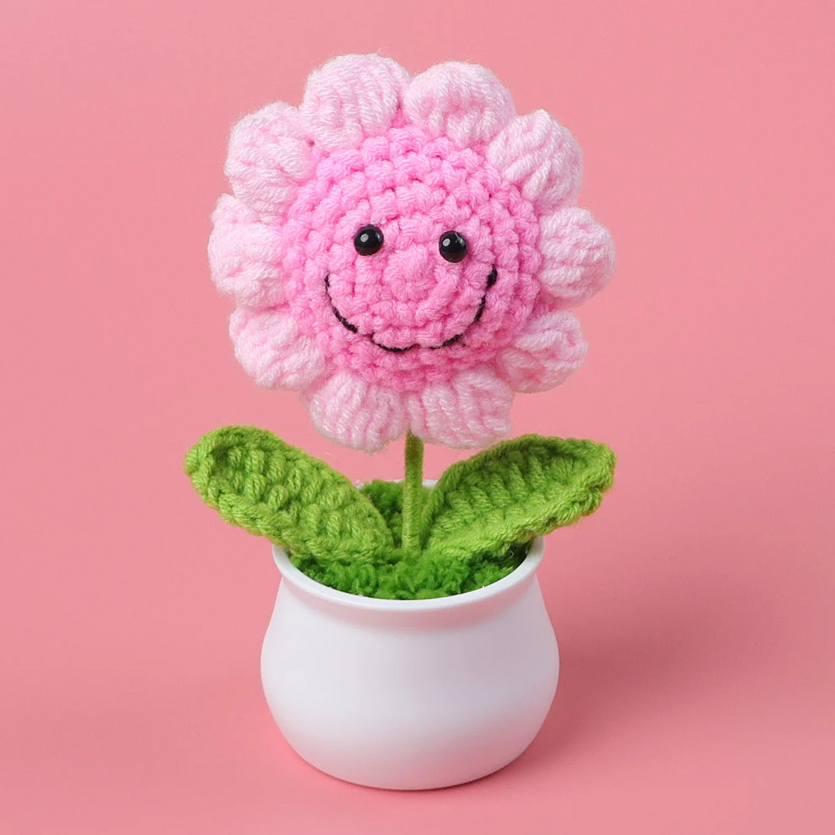 Handcrafted crochet pink sunflower with green leaves planted in a white pot