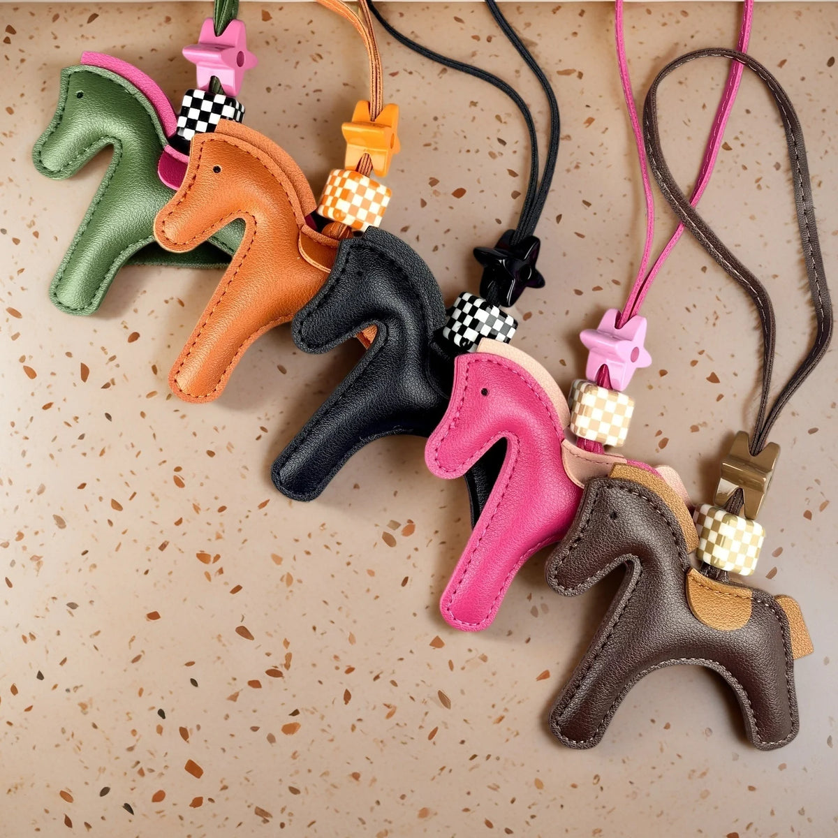 A collection of leather pony charms in various colors including green, orange, black, pink, and brown.