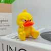 A bright yellow 3D printed duck statue with an angry expression sitting on a white box.