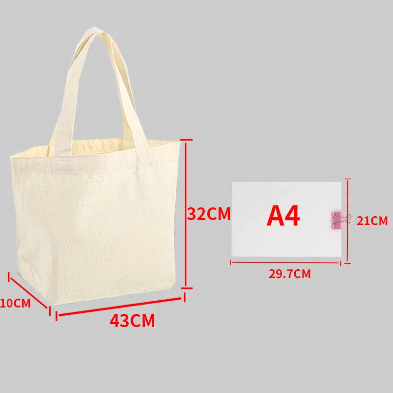 A beige canvas shopping tote bag shown next to an A4 sized card for scale.