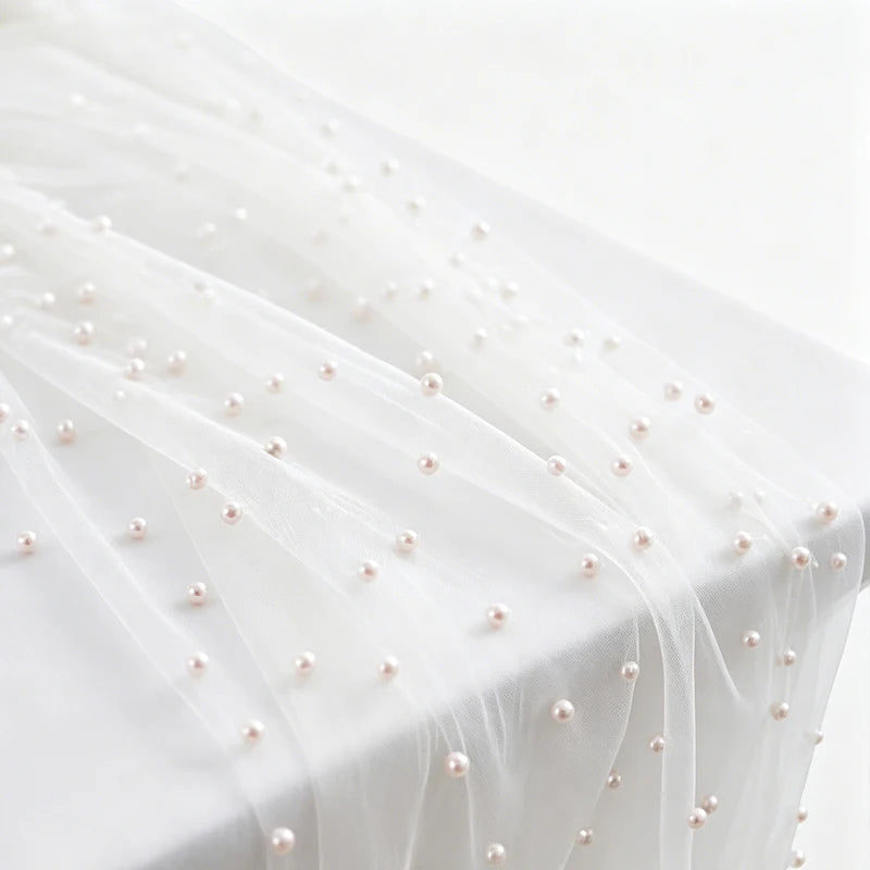 White tulle table runner adorned with small pink faux pearls.