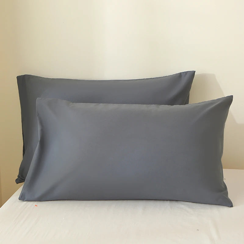 A set of two solid gray premium brushed fabric pillow covers resting on a white surface.