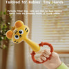 A hand is holding a yellow cartoon animal rattle toy with an orange ring for baby grasping practice.
