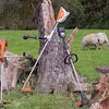 A steel wire wheel brush attached to a pole is shown in a grassy field.