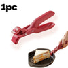 A red silicone bowl and plate gripper clip is shown being used to lift a sandwich from a dark silicone plate.