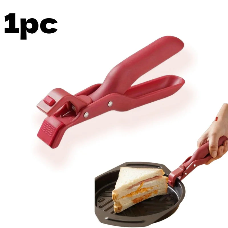 A red silicone bowl and plate gripper clip is shown being used to lift a sandwich from a dark silicone plate.