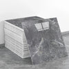 A stack of rectangular gray marble tiles next to a single tile showing veining and a window pattern.
