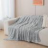 A soft gray brushed flannel throw blanket draped over a light-colored sofa.