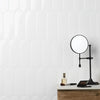 A black magnifying mirror is displayed on a wooden surface against a white, ribbed wall.